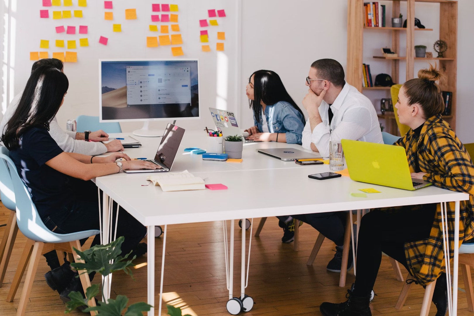 Weißer Tisch mit Monitor, an dem fünf Personen sitzen und in Richtung Bildschirm blicken, INCA Technologiezentrum GmbH